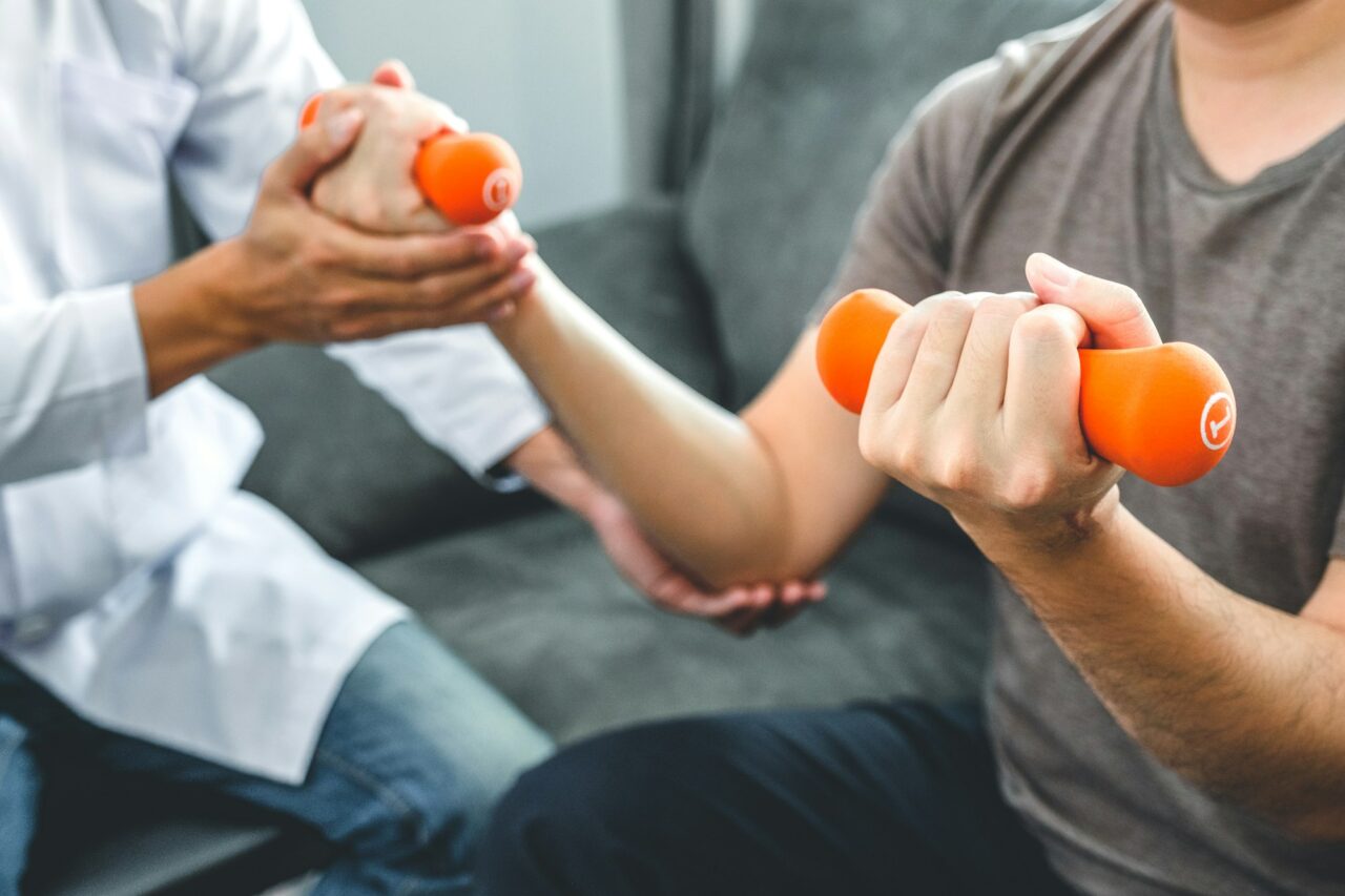 Physiotherapist man giving exercise with dumbbell treatment